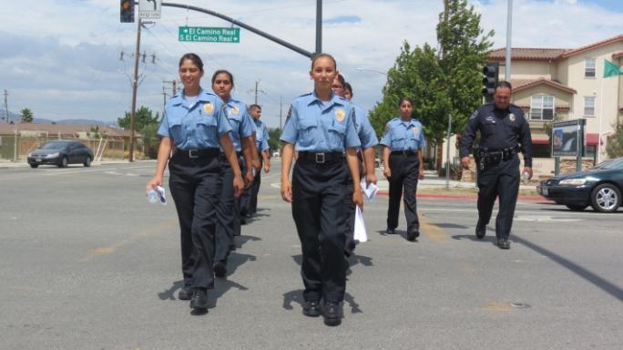 Young women marching in police uniforms.